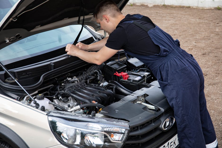 Mechanic working on a car engine with hood open, showcasing automotive repair skills.